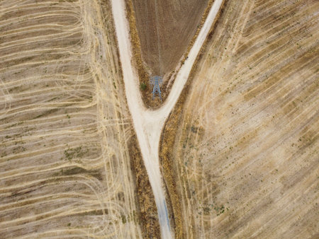 This aerial perspective reveals a striking agricultural area featuring two intersecting dirt paths surrounded by freshly plowed fields.の写真素材