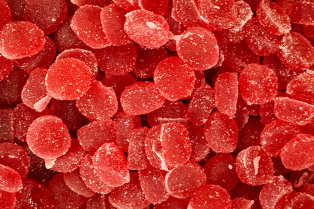 Colorful red gummy candies are arranged attractively in a market stall. They glisten with sugar and catch the eye of passersby, creating a tempting treat.の写真素材