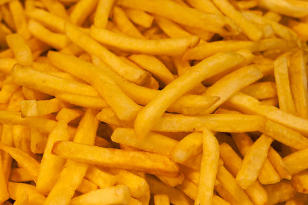 A large pile of crispy golden fries fills the scene, showing their perfect texture and color, ideal...