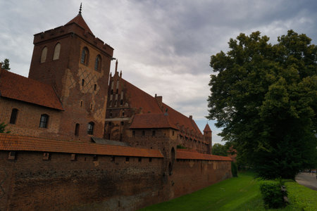 Visitors admires the grandeur of a historic castle featuring red brick architecture against a...