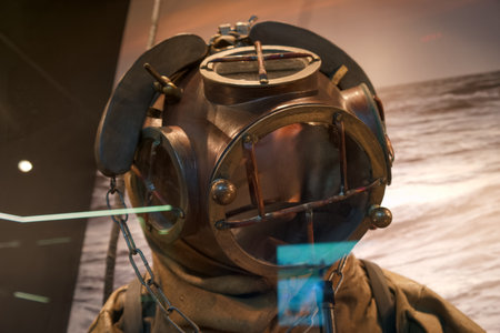 A vintage diving helmet from the 1900s is displayed at a maritime museum. The helmet features metal...