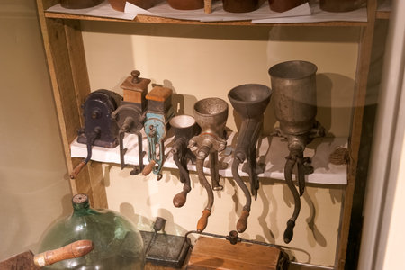 A variety of vintage kitchen tools are arranged on a wooden shelf in a museum.の写真素材