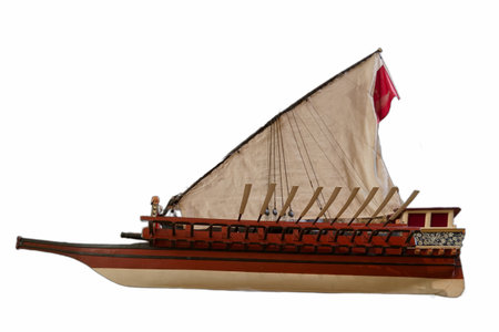 A detailed wooden model of a sailing ship features a tan sail and several oarsmen. The craftsmanship...