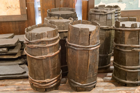 Several wooden barrels and containers are arranged in a rustic display, showing their worn textures and sturdy construction against a backdrop of historical items.の写真素材