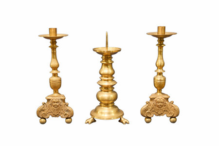 Three brass candle holders stand prominently, highlighting their unique shapes and detailed engravings. They add a touch of elegance to home decor.の写真素材