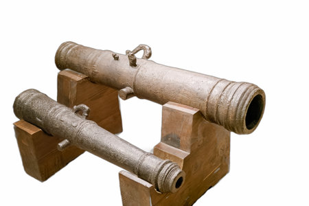 Two vintage cannons are displayed on wooden stands in a museum. The cannons, made of metal,...