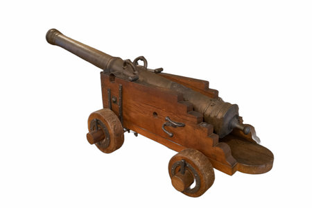 A handcrafted wooden cannon model stands ready on a plain white surface. Its metallic barrel gleams and showcases intricate details, reflecting historical craftsmanship.の写真素材