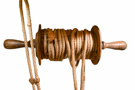 A wooden spool displays neatly coiled rope, emphasizing craftsmanship and practicality. This object...