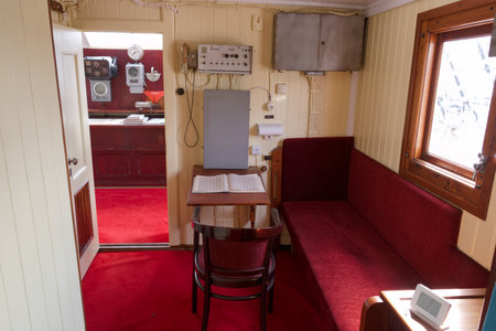 A small room showcases red upholstery on a bench and chair. A wooden table is in the center, with...