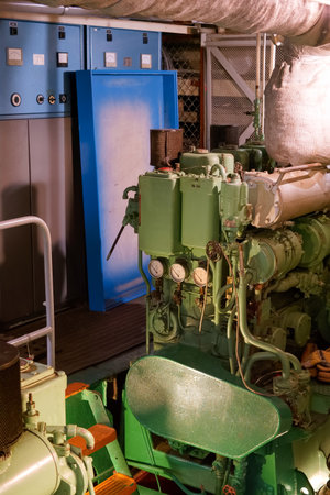 A detailed view of machinery components in a control room at a marine engine facility. Green...