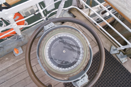 A navigational compass is centered in the image, showing clear markings. Surrounding it are parts of the ship's deck and railings. The setting is peaceful with soft lighting.の写真素材
