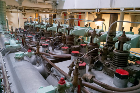 Intricate engine room machinery reveals various mechanical components connected by pipes and valves....