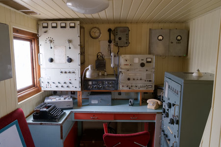 This control room features vintage communication equipment set against warm wood panels. A desk,...