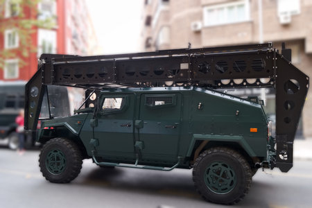 An armored vehicle stands on a city street, featuring a high tech platform on top. The scene captures the vehicle's robust design and advanced functionality under bright daylight.の写真素材