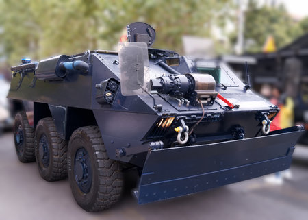 A heavy armored vehicle is showcased at a community event, surrounded by onlookers. This six wheeled...