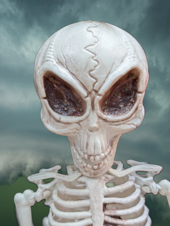 A detailed skeleton figure with a cracked skull and large dark eyes stands against a mystical cloudy...