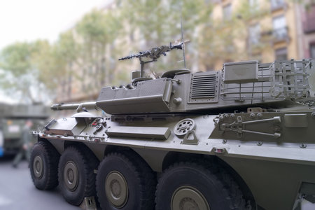 A military tank is parked on a city street, surrounded by buildings and trees. The tank features a...