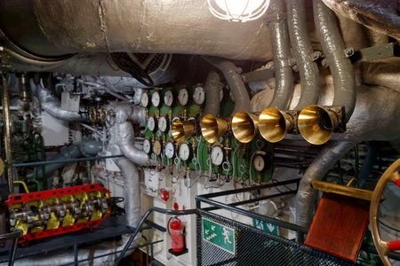 In a ship's engine room, various gauges and pipes are visible. Technicians are checking equipment as...