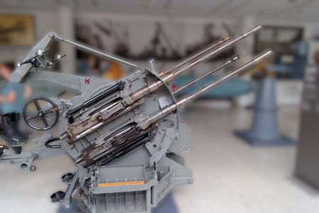 Visitors explore a military museum featuring a historic artillery piece with multiple barrels. The...