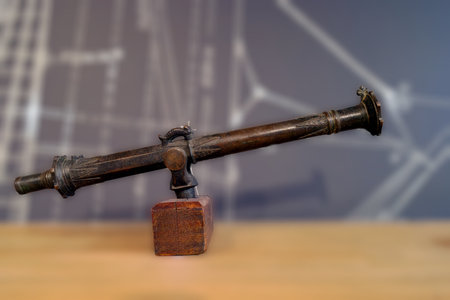 A historic telescope remains on a wooden base, surrounded by a detailed blueprint backdrop. The telescope showcases antique craftsmanship and serves as an educational exhibit in a museum.の写真素材