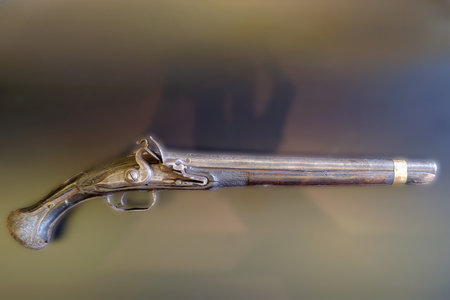 A flintlock pistol rests against a dark backdrop, showing its intricate design and historical value....