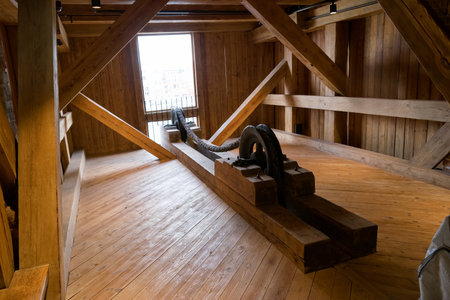 Inside a historic building, a wooden interior highlights a large beam, illuminated by natural light coming through a nearby window. The space radiates warmth and craftsmanship.の写真素材