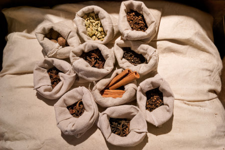 An array of spices is arranged in small fabric bags on a soft surface. Each bag contains different types of spices, showing their rich colors and textures.の写真素材