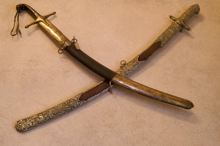 Two beautifully crafted antique swords are arranged in a crossed formation, highlighting their ornate handles and detailed scabbards, perfect for collectors or history enthusiasts.の写真素材