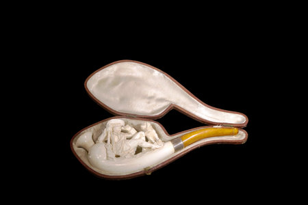 A beautiful porcelain pipe displayed in an elegant case. The pipe features intricate designs and a yellow stem, reflecting fine craftsmanship from the 19th century.の写真素材
