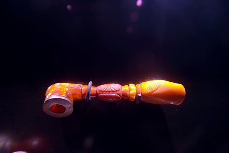 This carved orange artifact features detailed designs and craftsmanship. Its unique shape and...