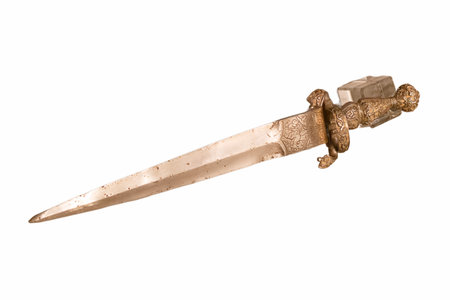 A detailed view of a decorative dagger rests on a clean surface, highlighting its ornate handle and unique blade design under bright light. The craftsmanship emphasizes artistry.の写真素材