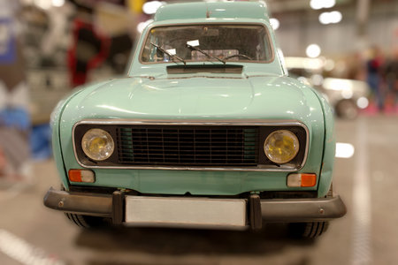 Classic mint green car showcased in an auto exhibition. The vehicle features round yellow headlights and a retro design, capturing the essence of vintage automotive style.の写真素材