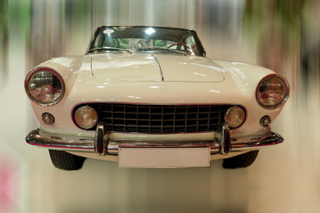 A classic sports car is showcased in a contemporary exhibition hall. The sleek design and polished finish capture the attention of visitors. Bright lights enhance its charm.の写真素材