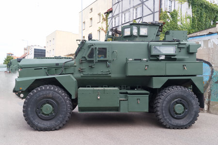 A military armored vehicle is stationed on a city street. The sturdy design features large wheels...