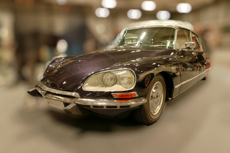 A classic car stands on display in a retro themed venue. The vehicle features elegant curves and...