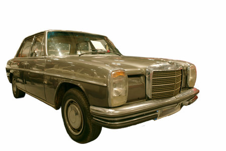 A vintage car stands on display in a museum. The exterior shines under lights. Visitors admire its...