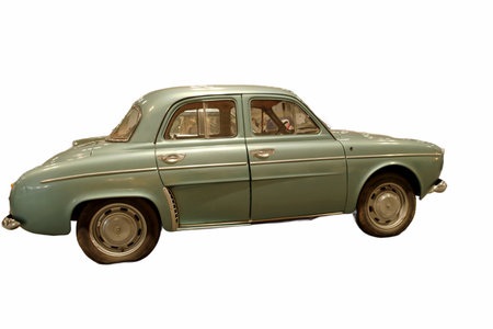 A light colored classic car is stationary on a street. The vehicle has a smooth design and shiny...