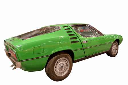 A green sports car sits on display at a vintage car exhibition. The model, from the 1970s, captures attention with its distinct design features and shape. Visitors admire the vehicle.の写真素材
