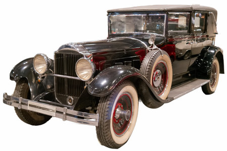 A vintage black car is parked inside a museum. The car features shiny chrome details and large whitewall tires. The setting includes other classic cars and automotive displays.の写真素材