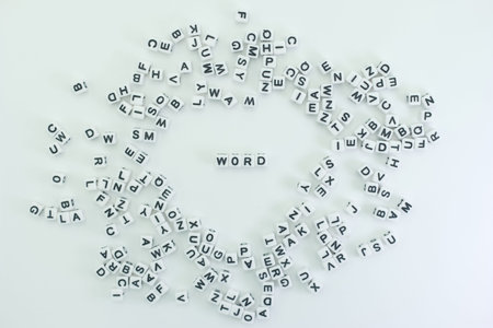 Letter tiles are scattered on a white surface, forming a unique pattern. The focus is on the word WORD made from the same tiles. This activity appears to be playful and engaging.の写真素材