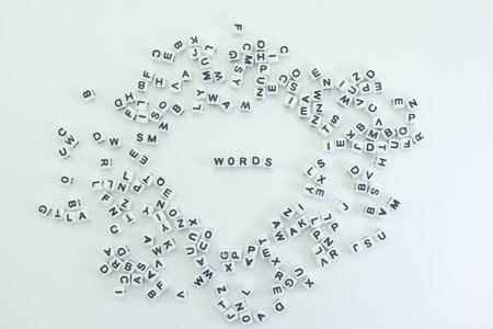 White letters are arranged randomly on a smooth surface. In the center, the word words stands out. This setup showcases the concept of language and communication.の写真素材