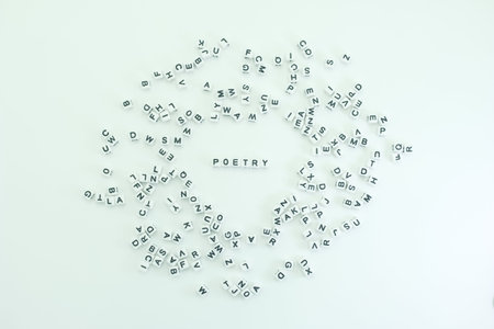 Many letters are scattered on a flat surface. The word poetry is placed in the center surrounded by different letters. This shows a creative approach to language.の写真素材