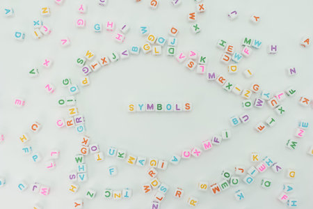 Colorful letter blocks are scattered on a white surface. Some letters are arranged to form the word symbols. This activity takes place indoors in a bright setting.の写真素材