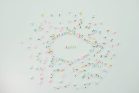 Small colored letters are scattered on a light background. The letters form the word chaos in the...