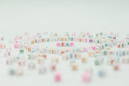 Small plastic letter blocks are spread out randomly on a light surface. One word in the center is...