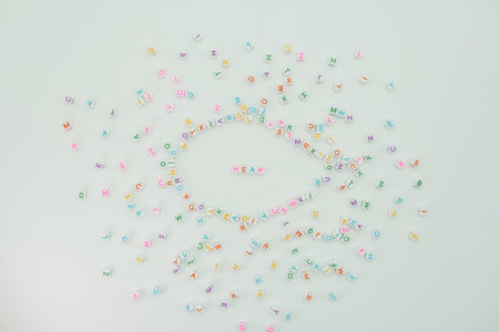 Plastic letters are spread across a light surface with many colors. The word heap is placed in the...