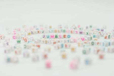 Beads with letters are spread across a white surface, creating a random mix. In the center, the word jumble stands out with colorful letters. This showcases a playful scene of letters.の写真素材