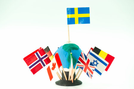 A small globe made of clay is shown with flags from various countries placed around it on...