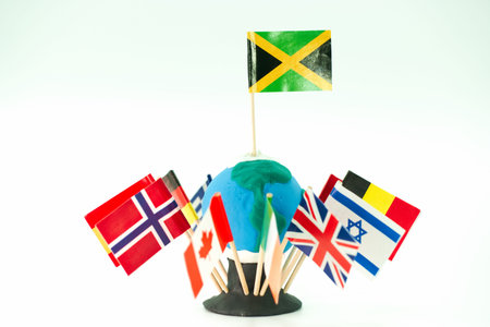 A model globe made of clay sits on a base with sticks holding various country flags. The flags...