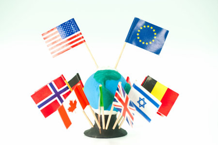 A small model of the Earth is made from clay. Several flags from different countries surround the...